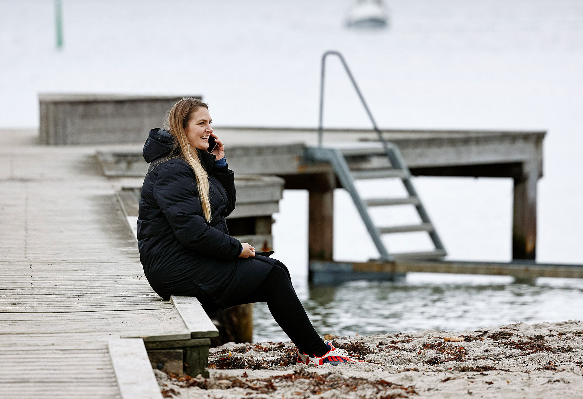 TDC NET Kvinde Ved Strand Siddende Pa Badebro Mobil Low Srgb